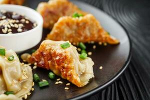 delicious fried gyoza dumplings on a black plate photo