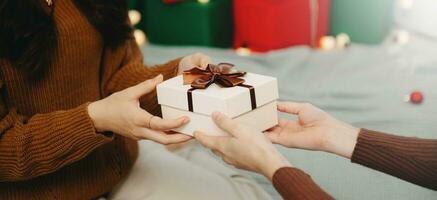 Happy woman giving Christmas and New Year Gift box to woman at Home.Family Xmas celebration. Christmas decoration. photo