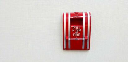 Fire alarm switch box for pull in case of fire isolated on grey or gray wall background with right copy space. Prevent emergency event concept photo