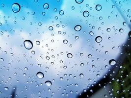 Water droplet or raining on glass with building, blue sky and cloud background concept. Beautiful of nature and season photo