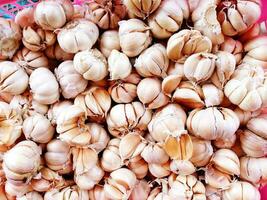 Many fresh garlic and cloves of garlic on the red net at street food market. photo