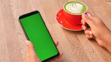 een cpu koffie vasthouden en een smartphone met groen scherm gebruiken video