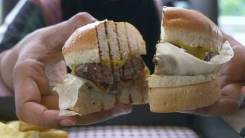 Mano sujetando hamburguesa de ternera en la mesa de cerca video