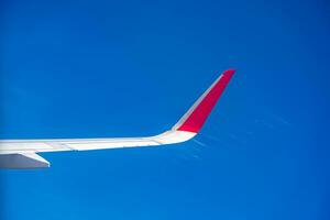 View from airplane window with blue sky and white clouds. Red tip photo