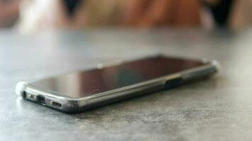 A hand grabbing and picking up mobile phone on the table. video