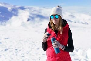 Smiling woman with bottle of water standing on snow photo