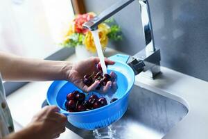 Anonymous woman washing cherries in sink photo