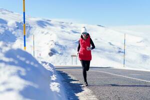 Female running on road in snowy mountains photo