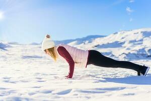 Young woman doing handstand press up on snow photo