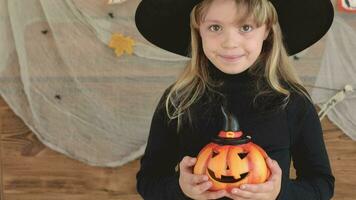 a little girl in a witch hat holding a pumpkin video