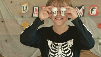 a boy wearing a halloween costume holding up two skulls video