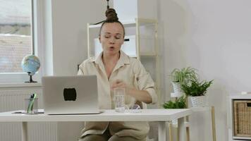 a woman sitting at a desk with a laptop video