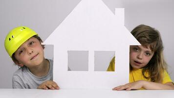 dois crianças segurando acima uma papel casa video