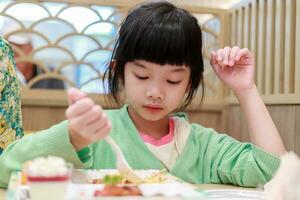 linda pequeño asiático niño niña comiendo comida foto