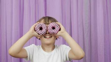 a little boy is holding two donuts in front of his eyes video