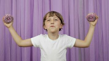 a young boy is holding two donuts in front of his eyes video