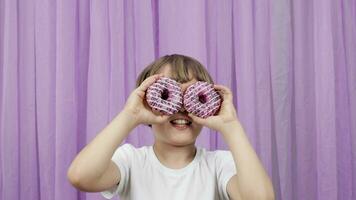 a young boy is holding two donuts in front of his eyes video