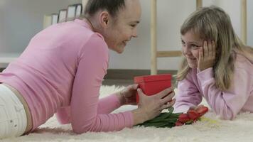 a woman and a little girl laying on the floor with a red box video