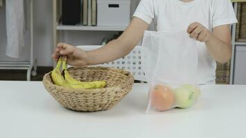 a person holding a bag of fruit in front of a basket video