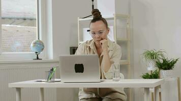 a woman sitting at a desk with a laptop video