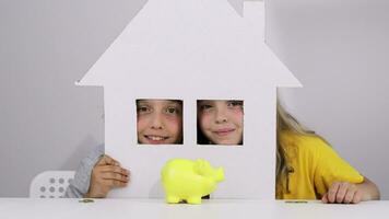 dos niños son mirando a un cerdito banco desde detrás un papel casa video