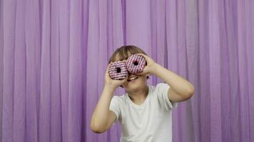 a boy is holding a donut in front of his face video