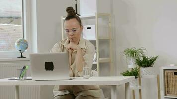 une femme séance à une bureau avec une portable video