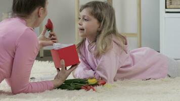 a woman and a little girl laying on the floor with flowers video