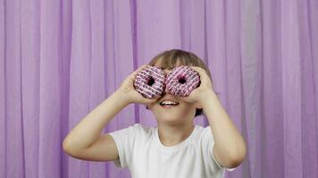 a little boy is holding two donuts in front of his eyes video