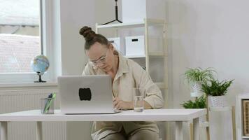 a woman sitting at a desk with a laptop video