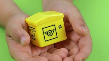 a child holding a yellow toy house on a green background video