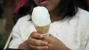 criança mão segurando baunilha gelo creme dentro uma waffle cone. video