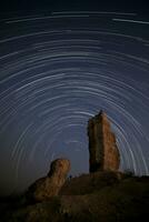 Star trail over large rock finger. photo