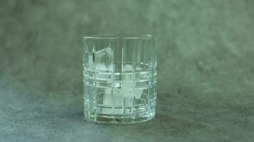 ijs kubussen vallend in een glas en rollend in de omgeving van. concept van koffie voorbereiding of zacht drankjes. video