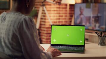 Freelancer using greenscreen on pc while working remotely on e commerce project, looking at isolated mockup template on laptop. African american person works with chromakey tech. video