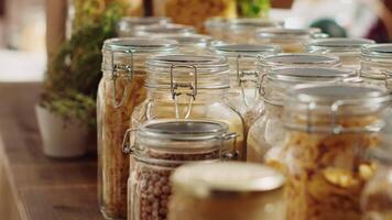 Close up on bulk products in recyclable glass containers used by zero waste supermarket to eliminate single use plastics. Local store pantry staples in sustainable packaging, zoom out shot video