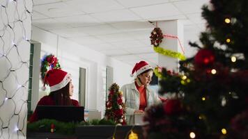 Jib up shot of worker in festive ornate office packing desk belongings on last day at work, leaving. Staff member getting fired from job during year end layoffs before Christmas, saying goodbye video