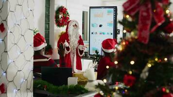 autorisé orateur habillé comme Père Noël claus Faire présentation dans de face de entreprise ouvriers en utilisant bonbons canne aiguille. Personnel apprentissage Comment à avance leur carrière pendant réunion dans Noël fleuri Bureau video