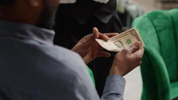 Hotel visitor pays cash for cup of coffee, handing money and tips to woman staff member in lounge area. Person requesting refreshment from bar service in lobby. Close up. Handheld shot. video