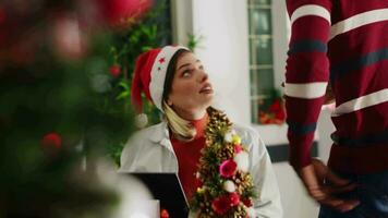 Employees wearing Santa Claus hat enjoying nice conversation in Christmas ornate office. Workers in xmas decorated workspace talking about festive winter holiday vacation plans video