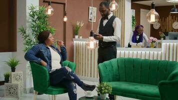 turist betalande för kopp av kaffe i hotell vardagsrum område, använder sig av kort till inköp förfriskning i lobby. kvinna resande framställning pos terminal betalning medan väntar till Registrera och kolla upp i. video