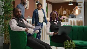 Employees of hotel checking information on papers and laptop, creating list of rooms for guests at reception lobby. At five star retreat, team of bellboy and receptionist oversee reservations. video