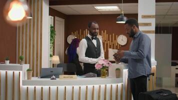 Hotel staff reviewing id papers for traveller arriving in lobby, preparing to do check in procedure and sign registration files with personal information. Guest travelling on holiday. video