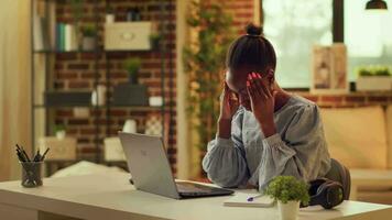 africain américain fille étant dans douleur à maison, Souffrance de extrême mal de crâne tandis que en essayant à résoudre du quotidien responsabilités. femme pigiste stressé à propos migraine, étant en dessous de pression. video