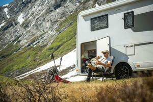 Tourist in Front of His Motor Home Taking Short Break to Eat Some Food photo