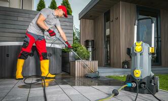 trabajador poder Lavado patio hormigón ladrillos utilizando presión lavadora foto