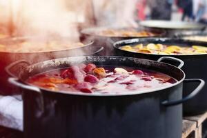 Beverages fruits and berries hot mulled wine in pots with steam in street food market. Generative AI photo