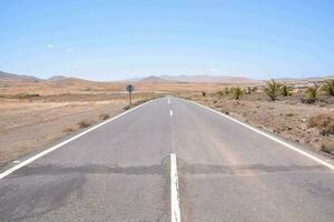 an empty road in the middle of the desert photo