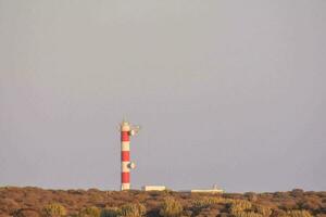 a red and white lighthouse on top of a hill photo