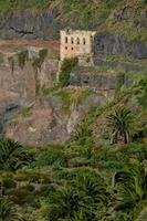 an old building sits on the side of a cliff photo